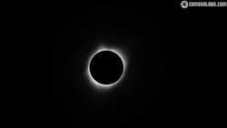 Total solar eclipse with the moon blocking the sun and corona visible as a bright halo against a black sky.