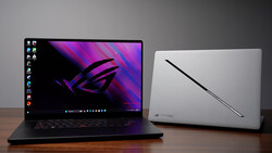 Two gaming laptops displayed on a wooden surface against a gray background.