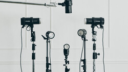 Professional studio lighting setup with five mounted light fixtures and overhead rigging against white walls.
