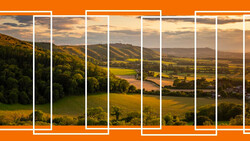 Rolling countryside landscape with agricultural fields and forested hills under golden hour sky.