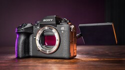 Sony α8 mirrorless camera body with open articulating screen, lit with purple and orange accent lighting against dark background.