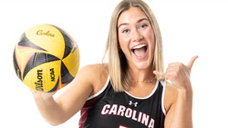 Athlete in Carolina tank top holding yellow and black volleyball while giving thumbs up.