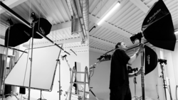 Professional studio setup with lighting equipment and a person adjusting a large softbox.