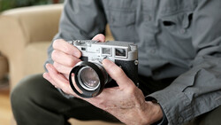 Hands holding a vintage rangefinder camera with a wide-angle lens attached.