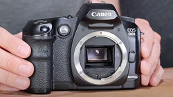 Canon EOS 60D DSLR camera body held in hands showing open mirror box and sensor.