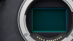 Camera body mirror with open shutter exposing the sensor and cyan-lit mirror box interior.