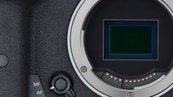 Close-up of a camera's mirror and sensor chamber with autofocus controls visible on the body.