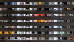 Apartment building facade at night showing illuminated windows across multiple floors with varied interior lighting and decor.