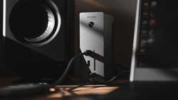 UGREEN power adapter mounted on wall with dramatic side lighting casting shadows. Warm and cool tones.
