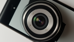 Close-up overhead view of a camera lens with metallic ring and green-tinted glass elements.