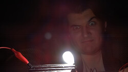 Person holding a bright LED light source close to camera in dark environment with red ambient lighting.