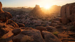 Desert town nestled among granite rock formations at golden hour sunset.