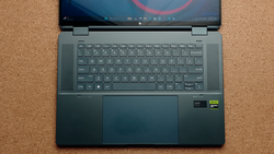 Laptop computer opened flat on cork surface showing desktop with circular design on screen.