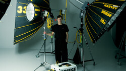 Professional film production lighting setup with large parabolic reflectors and a cinematographer in a controlled studio environment.
