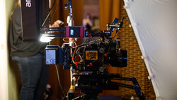 Professional cinema camera rig with mounted monitors, lighting, and support equipment on a carpeted floor.