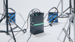 Three 3D printers with blue filament spools arranged on a white surface against a neutral background.