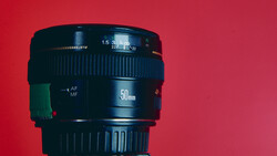 Black 50mm camera lens with autofocus markings against a red background.