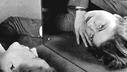 Woman lying on floor looking at mirror, black and white portrait photograph.