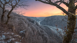 River valley at sunset framed by frost-covered trees and rocky canyon walls.