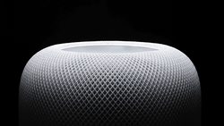 Close-up of a spherical speaker with a mesh fabric surface texture against a dark background.