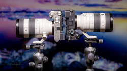 Two telephoto lenses mounted on ball head tripod mounts against colorful sky backdrop.