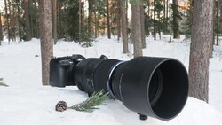 Professional telephoto lens mounted on mirrorless camera body in snowy forest setting.