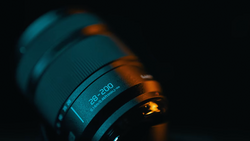 Close-up of a telephoto lens with 28-200mm focal length marking visible against dark background.