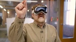 Man wearing VR headset with fist raised indoors.