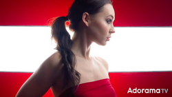 Woman in red strapless dress photographed in profile against red and white striped background.