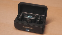 Saramonic wireless microphone system with charging case open on wooden surface.