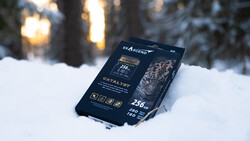 SSD storage device packaging positioned in snow with winter forest and golden sunlight in background.