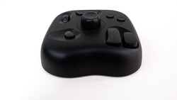 Black wireless game controller with rounded body and multiple buttons against white background.