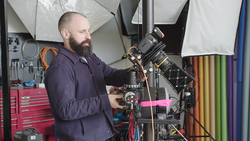 Cinematographer operating a professional cinema camera mounted on a rig in a studio setup.