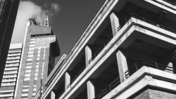 Black and white photograph of modern skyscrapers shot from below, emphasizing geometric lines and architectural contrast.