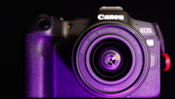 Canon EOS R5 mirrorless camera with RF 24-50mm lens bathed in purple studio lighting against a black background.