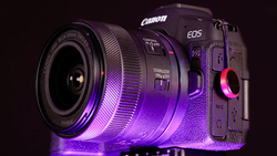 Canon EOS R5 mirrorless camera with attached lens, illuminated by purple and pink neon lighting against a dark background.