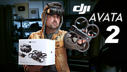 Person wearing FPV goggles and tan jacket holds DJI Avata 2 drone packaging while displaying the assembled quadcopter.
