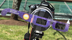 Canon DSLR camera with NASA-approved solar eclipse glasses mounted in front of the lens.