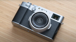 Rangefinder film camera with black leather body and silver top plate on wooden surface.