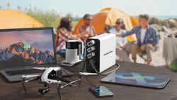 Photography and camping gear arranged on a wooden table with tents and campers visible in the background.