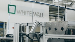 Industrial manufacturing facility with White Wall branding visible on white wall signage above machinery.