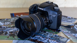 Canon EOS DSLR camera with attached lens resting on printed photographs.
