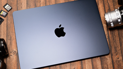 MacBook Pro laptop with closed lid displaying Apple logo on wooden surface surrounded by camera equipment.