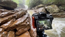 Camera mounted on tripod displaying live view of flowing river and rocky canyon landscape.