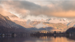 Alpine lake with snow-capped mountains reflected in still water at golden hour.