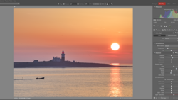 Sunset over water with silhouetted cityscape and small boat in foreground.
