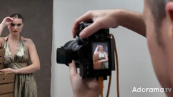 Photographer holding a DSLR camera with model visible on LCD screen during portrait shoot.