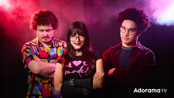 Three people posing against a pink and purple gradient backdrop with dramatic colored lighting.