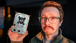 Person holding a decorative hard drive with skull and crossbones design labeled RIP.