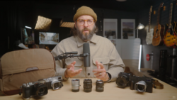 Photographer demonstrating vintage camera lenses arranged on a table during a studio discussion.